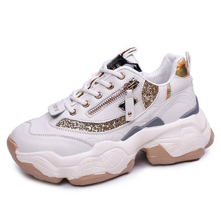 White leather and gold glitter women's chunky sneakers with a side zipper detail and a thick platform sole. The sneakers have a sporty, casual style with a touch of glamour.