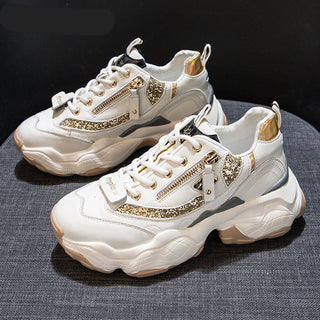 Stylish women's sneakers with golden accents. The chunky, white sneakers feature lace-up closures, side zippers, and metallic gold details that add a touch of glamour. The textured, platform soles provide a trendy, elevated look.