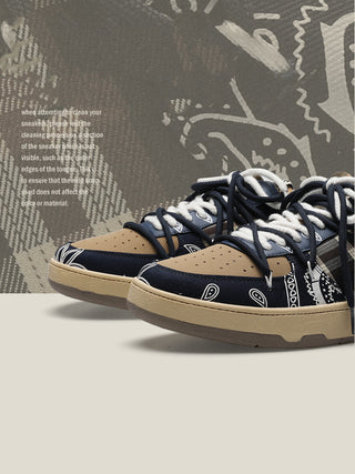 Stylish fitness sneakers with navy blue and tan colors, featuring a distinctive patterned design on the upper. The sneakers are placed against a textured, graffiti-style background, adding a dynamic visual element to the image.