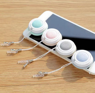 Pastel-colored macaron-shaped screen cleaner set with smartphone on wooden table