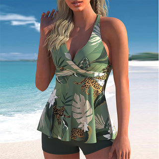 Green tropical floral swimsuit with leopard print details on beach against blue sky