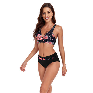 Floral printed two-piece swimsuit featuring a halter-style crop top and high-waisted bottoms, worn by a smiling young woman with long dark hair.