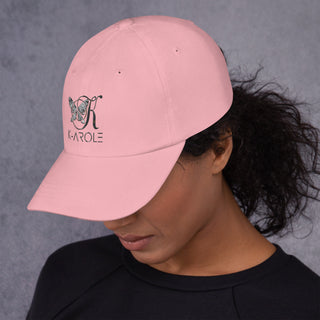 Pink fashion cap with K-AROLE logo and butterfly graphic, worn by a person with curly dark hair against a gray background