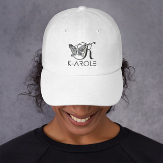 Sleek white K-AROLE branded dad hat with stylized logo, worn by smiling young woman against dark gray background.