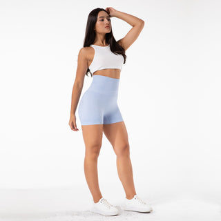 Comfortable high-waist seamless blue yoga shorts worn by a woman with long dark hair, paired with a white crop top on a plain background.